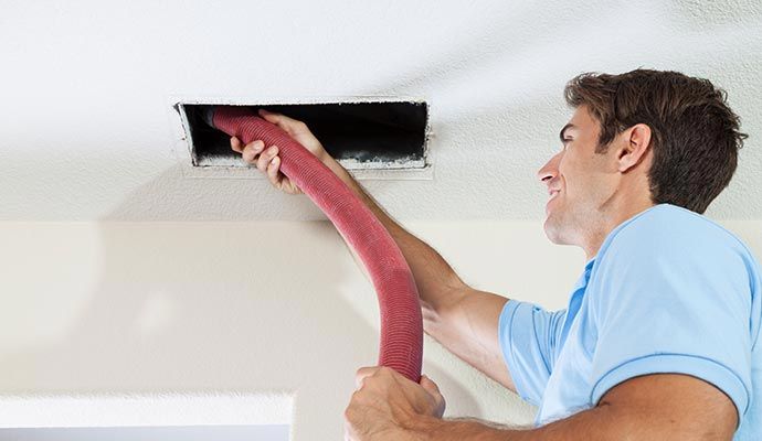 Person cleaning air duct with equipment