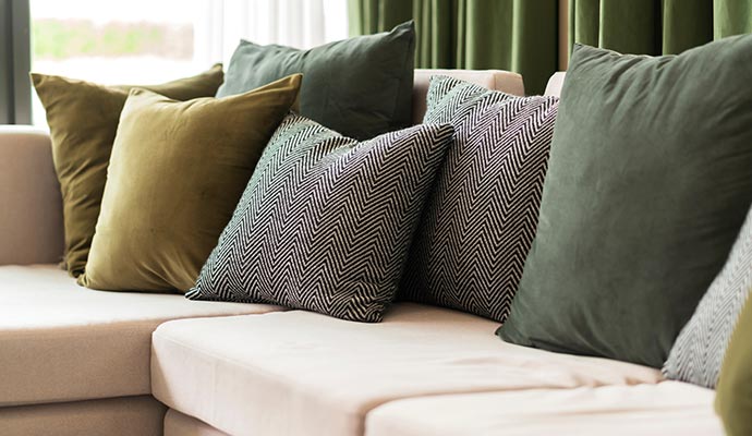 A collection of colorful patterned throw pillows arranged on a gray sofa