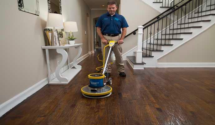 Person cleaning wooden floor with equipment