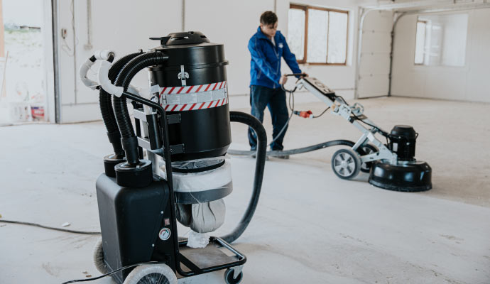 Professional worker cleaning concrete floor with industrial equipment