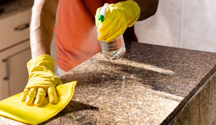 A person is cleaning a granite countertop